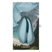 Powder blue Womanizer Liberty clitoral stimulator in packaging with a scenic background.