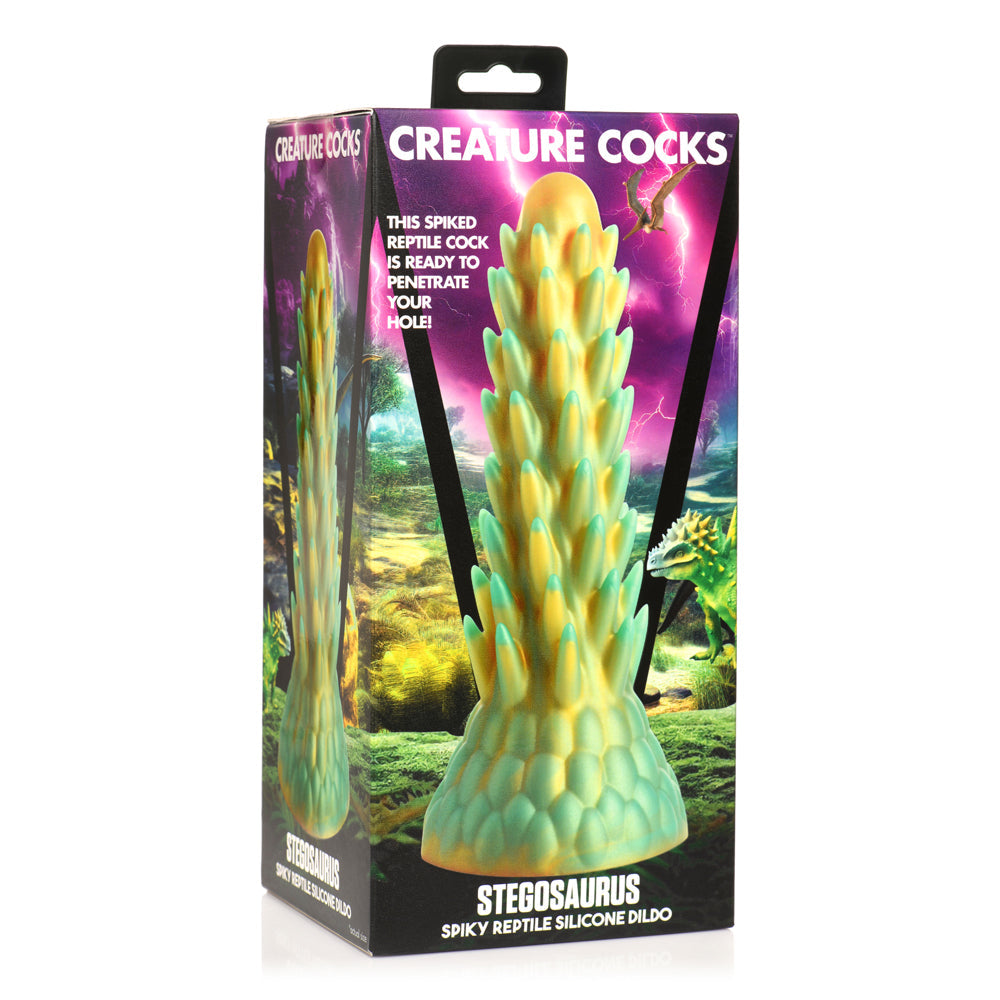 A spiky, green and yellow silicone dildo shaped like a stegosaurus on a box.