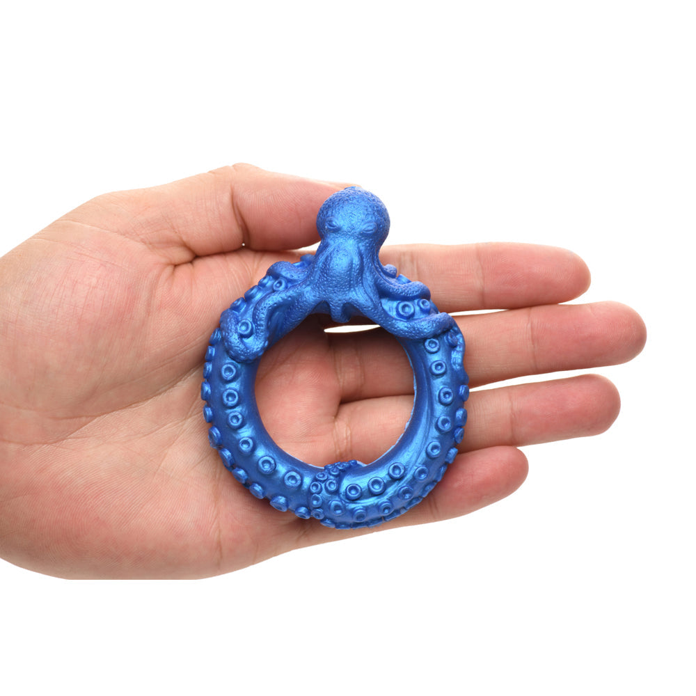 Blue octopus-shaped silicone cock ring held in a hand.