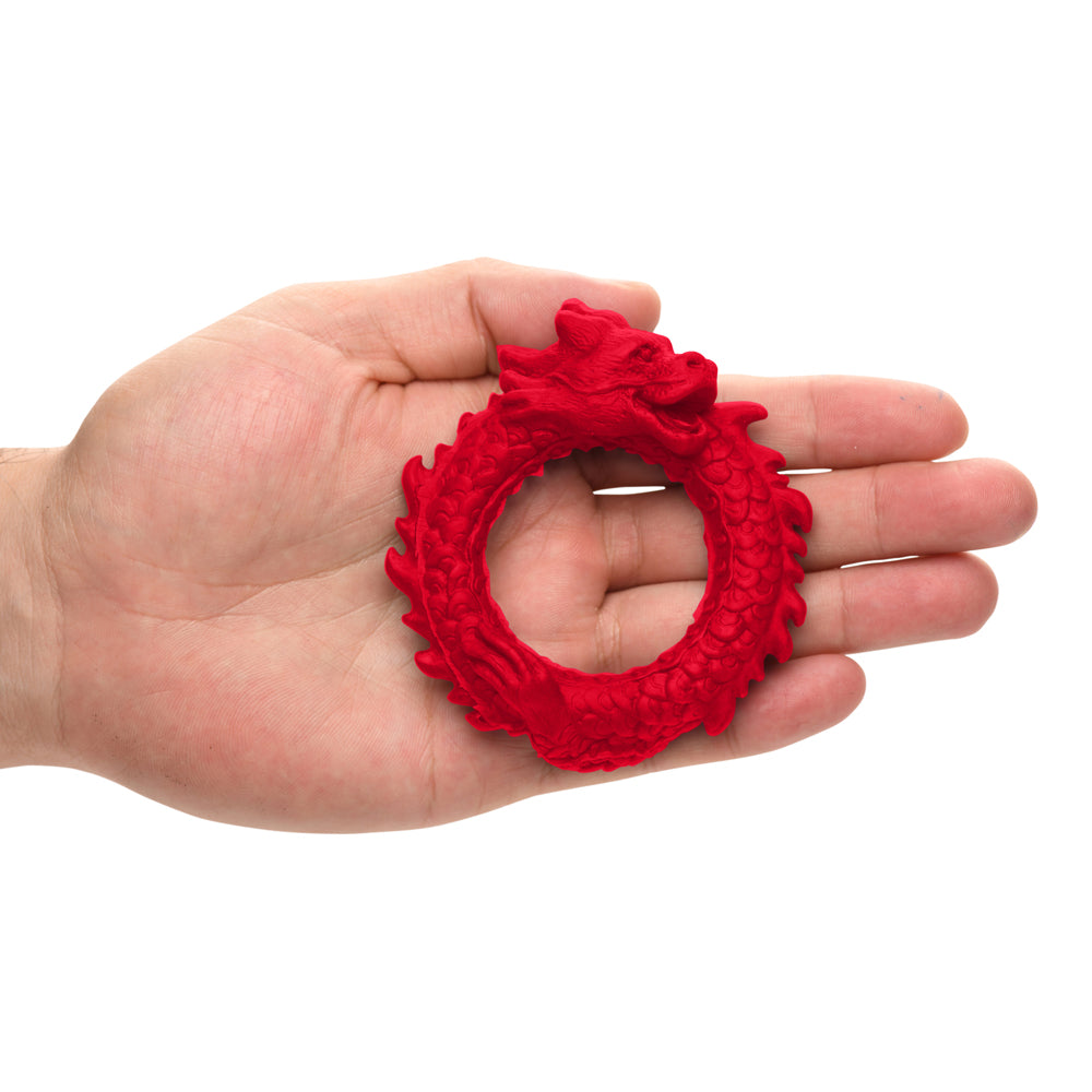 Red silicone dragon-shaped cock ring held in a hand.
